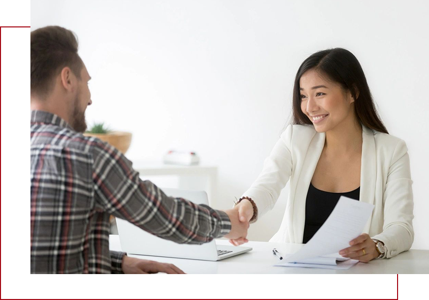 A man and woman shaking hands over papers.